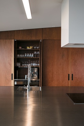 Full-height plywood cabinetry lends visual warmth to the streamlined kitchen. 
