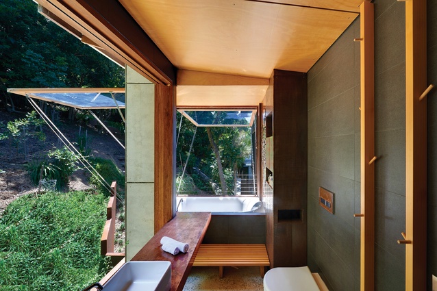 In the ensuite, a floor-to-ceiling retractable window opens the western wall to the bush.