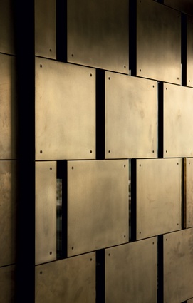 A detail of the brass-finished metal wall, a section of which is operable, to provide privacy in the dining room.