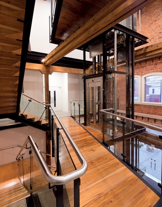 In the foyer, a new glass, steel and timber stair and lift structure stands against the backdrop of the brickwork shell.