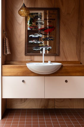 The powder room with repurposed rimu bench and basin, featuring a late father's pride and joy — the Ford Falcon GT mirror.