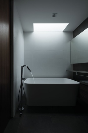 Light streams into the bathroom from above, illuminating a Victoria & Albert Edge free-standing bath.