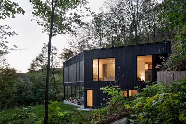 The Rock, Quebec, Canada, by Atelier General. 2017. The home is clad in black-painted timber and is topped with a flat roof in order to merge in with the mountain surroundings.