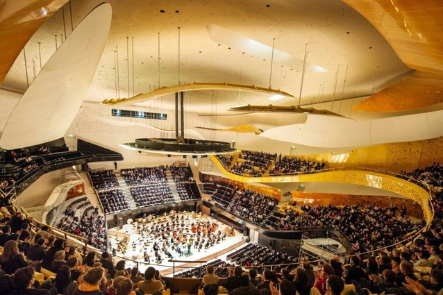 Philharmonie de Paris, France by Jean Nouvel. A stark contrast to the exterior of the building, this warm, glowing space is framed by curving forms with cascading balconies that wrap around the stage.
