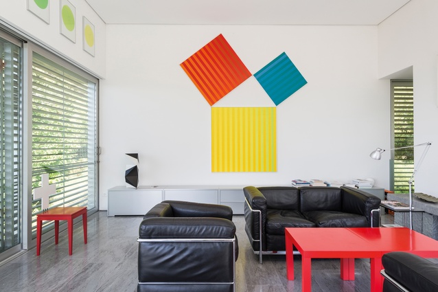 The living room suite, designed by Le Corbusier, has been placed around two red Ikea tables. 