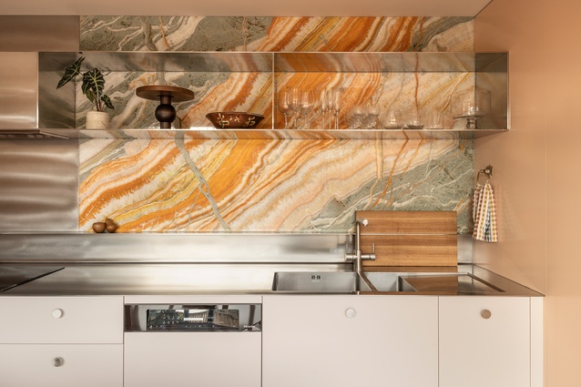 The stunning rainbow onyx splash back is the centre of attention in the kitchen. Also note bespoke chopping board rack and shelves.