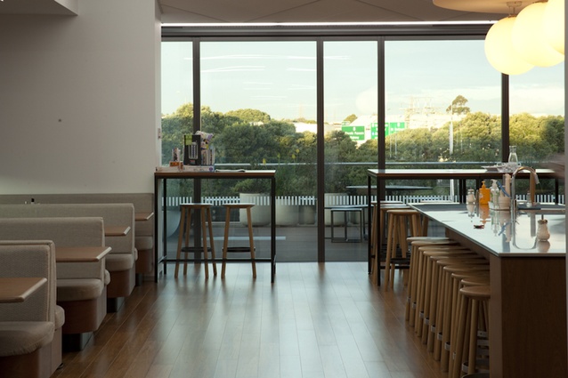 The communal dining area with open-plan kitchen islands flows to an outdoor barbecue area, with planters containing tussocks and edibles.