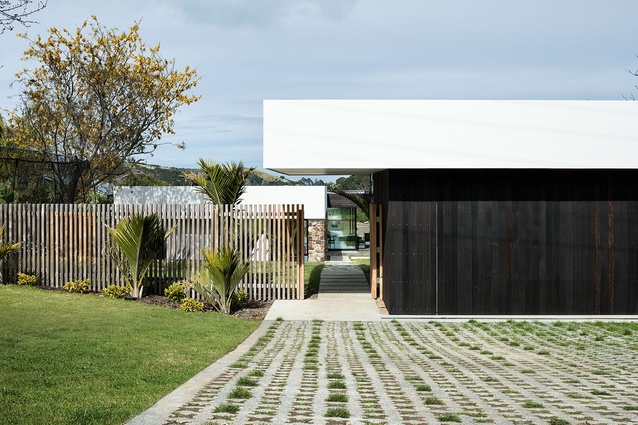 The L-shaped house, uniting with a garage and cantilevered entry canopy, frames a terraced courtyard garden on three sides.