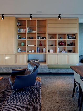 The expansive shelving and storage cabinets extend along a main wall and incorporate a fireplace. 