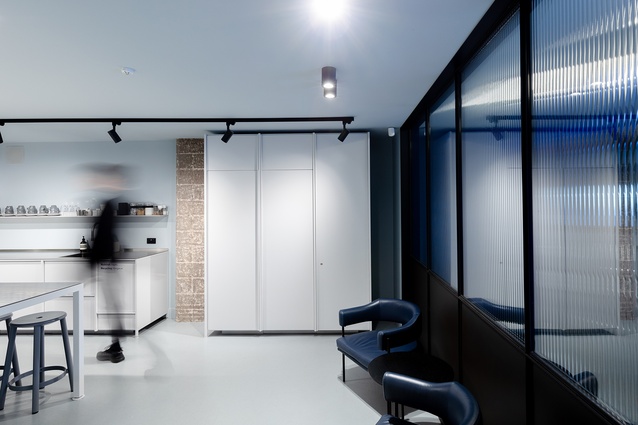 A white-steel KXN modular kitchen with a large steel-framed island anchors the space. The kitchen doubles as a working area for functions and food photography, with a restrained aesthetic expression painted in blue-grey.