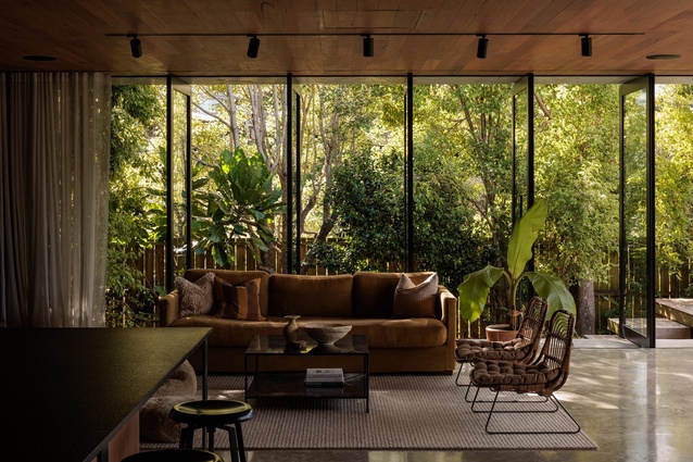 The living space opens to the outdoors through both pivoting and sliding apertures.