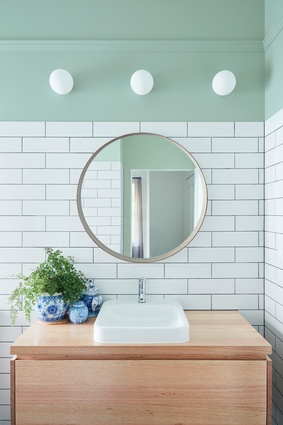 The green paint chosen for the bathroom, also referenced in the kitchen pendant lamp, assists in creating a tranquil space.