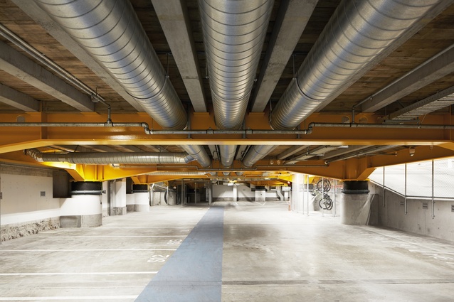 Massive steel beams in yellow clearly designate the structure beneath the ground-floor plinth.
