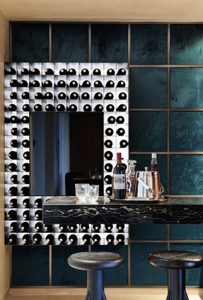 The minibar features a blue velvet fabric and metal grid backdrop and metal wine shelves painted black with electrostatic paint. 