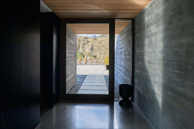 Shuttered concrete flanks the entrance way to this Queenstown home, carrying from the outside through to the interior.