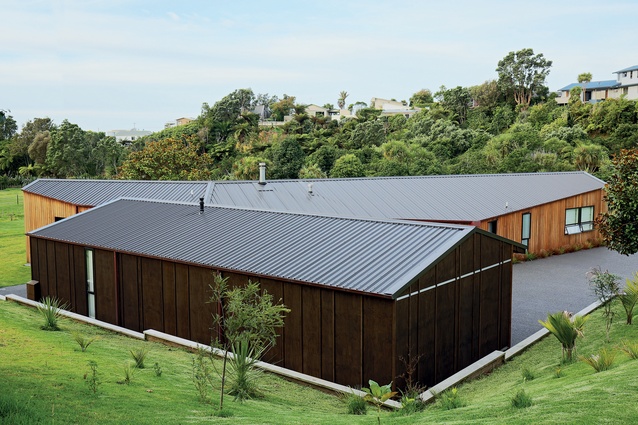 The dark-stained gaboon ply of the guest wing and garage contrasts the home’s western red cedar cladding.