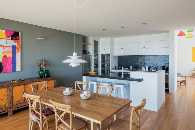The kitchen is tucked into a corner, allowing the open-plan living spaces to flow seamlessly from one to the other. 