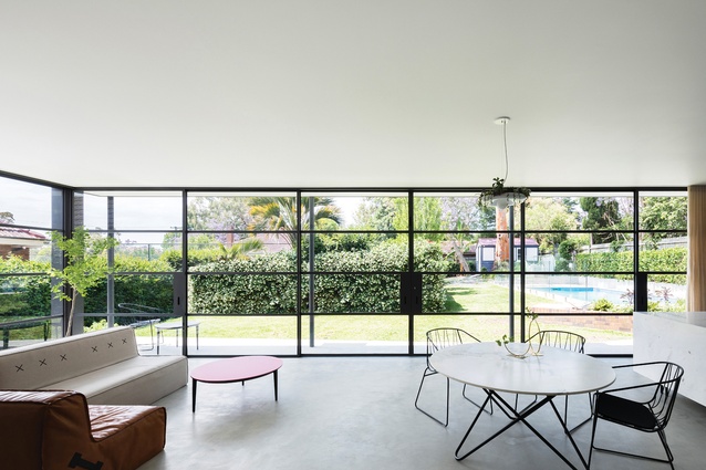 The kitchen, dining and living room look out to the garden through glass walls and sliding doors framed in fine steel. 