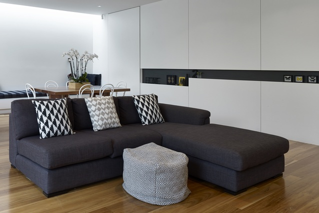The open-plan dining and living area features a strict palette of white, black, grey and wood. 