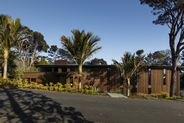 Tawini House, Titirangi. The house is built on a steep site and gives away little to the street, with vertical windows that allows glimpses in or out.