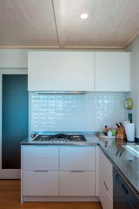 The kitchen is modest, minimalist and easy to clean, with stainless-steel benches and white tiles and cabinetry.
