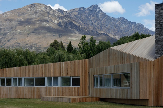 The cedar-clad house unfolds in front of the mountains.