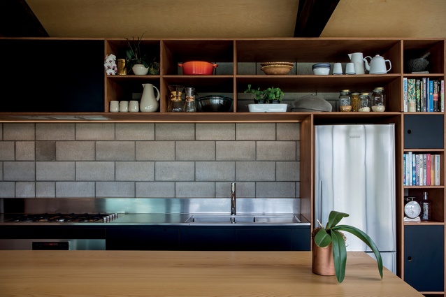 Bespoke timber cabinetry contrasts the breeze-block concrete wall.
