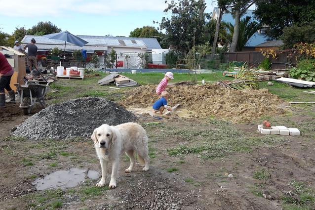 Evie Payne (the dog) on site with Isabelle & Nicolas working in the clay excavation pile from the ETS beds. Garry and Joel Payne in the background working on ramming the playhouse walls.