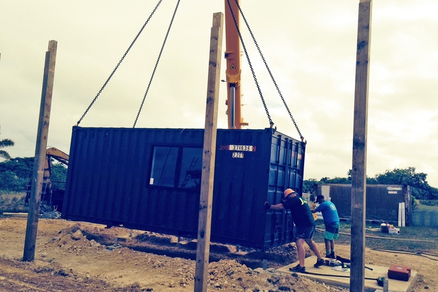 The shipping container is lowered onto its footings in preparation for becoming a services block.