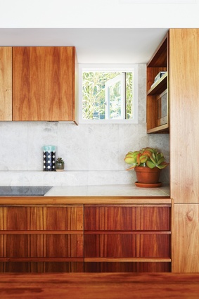 A strategically placed picture window in the kitchen offers sunlight and a glimpse of nature while maintaining privacy.

