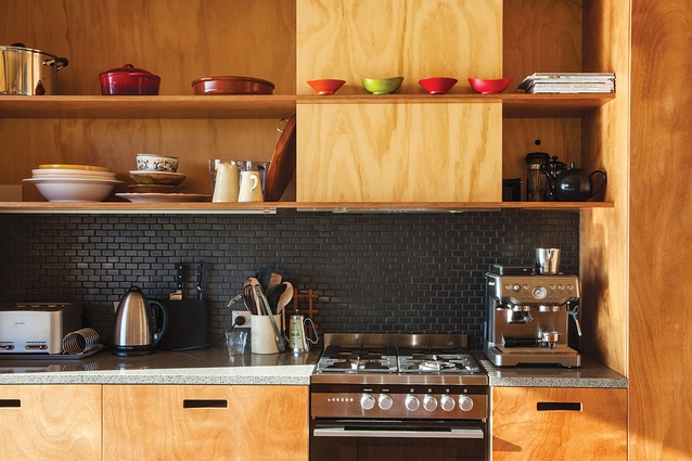 In the kitchen, the dark-tiled splashback contrasts with the ply walls and cupboards. 