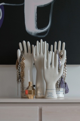 A group of vintage porcelain hands sits atop a dresser.