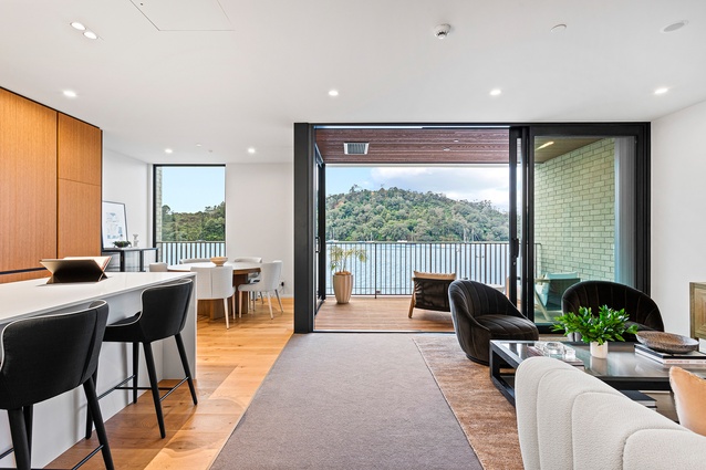 A view north from the top level of a Wharf Terrace townhouse showing kitchen and living spaces with the Waitematā and nature reserve beyond.