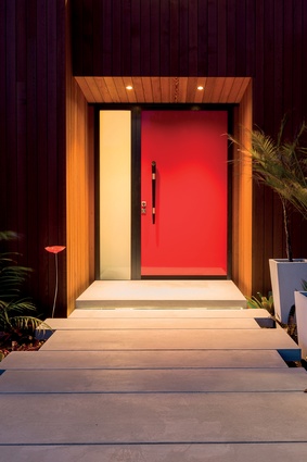 The red entry door augments the black and timber palette and is a hint to what lies beyond. 