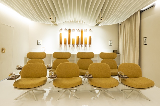 A dramatic eight-seat theatre features an undulating white ceiling that blends into the rendered curved wall and gloss-white floor.