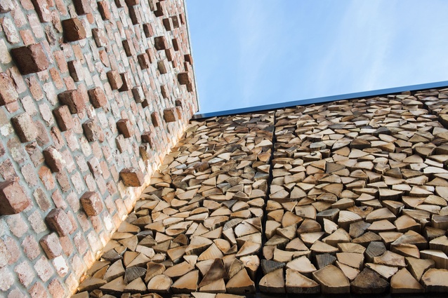 The textured wall surface of firewood and brick in the outdoor atrium.
