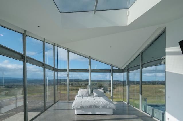 Enclosed on three sides by glass, the main bedroom rises to almost double height, punctuated by a skylight.