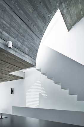 An expressive, curved concrete light-scoop adds drama to the kitchen.