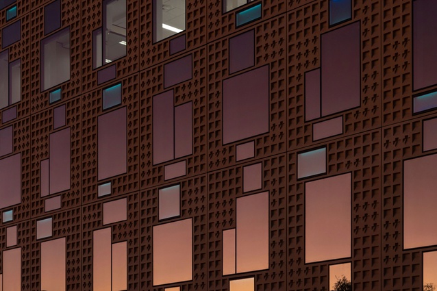 The matte waffle-textured façade interplays with reflective glazing and colour to create visual interest.