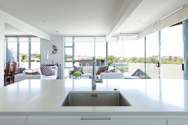 The kitchen forms part of a light-filled open-plan living area with panoramic views. The sculpture on the real wall is by Ray Haydon. 