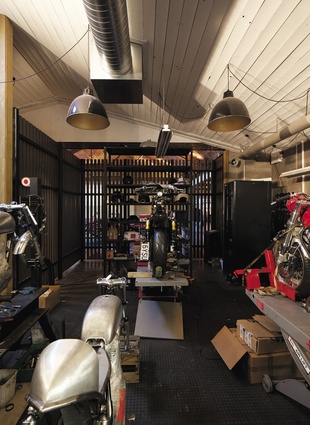 The custom motorcycle workshop is discreetly positioned behind slatted timber battens.