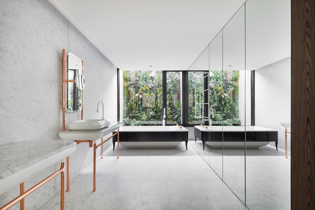 The bathroom’s mirrored walls and views to greenery create an inviting atmosphere, the marble surfaces and copper-finished fittings adding a touch of opulence.