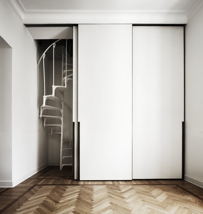Sliding doors with minimalist and modern detailing hide a staircase leading to a small guest room.