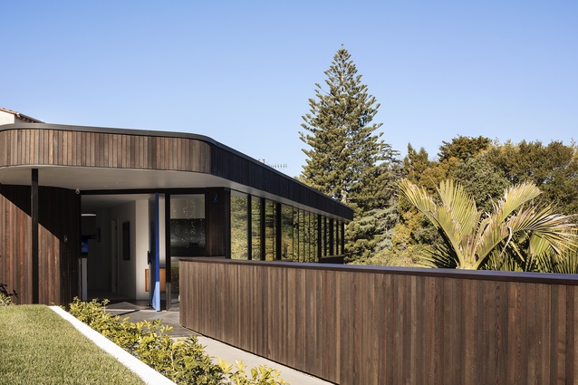 A tidy walkway takes you from the street to a light blue front door recessed within smooth cedar wood corners, aesthetics which are reoccurring throughout the exterior of the house.