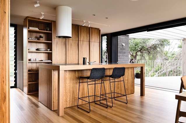 The timber kitchen island bench appears more as furniture than a functional cooking platform.