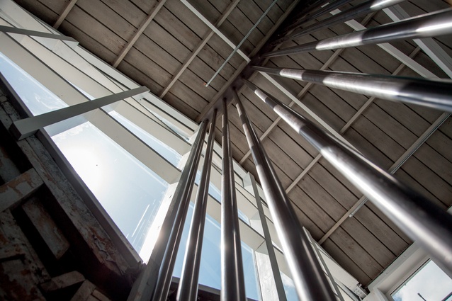 Polished steel bars create a vertical axis, leading the eye up to the highest point of the roof.