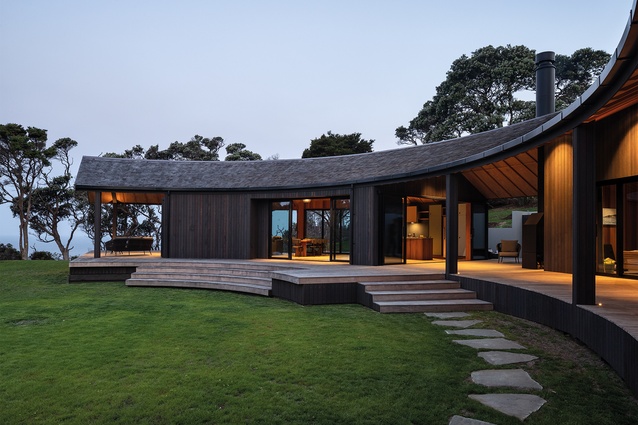 Living and sleeping wings are connected by a covered courtyard space, which forms part of an expansive deck that flows to a circular lawn.