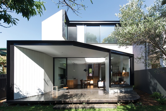 The rear elevation’s strong angles are defined by thick, black steel window reveals that contrast against the white plywood cladding.
