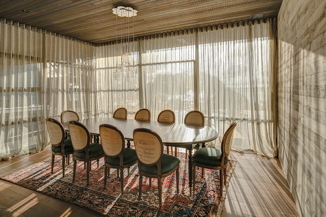The dining room with light pouring in through the lightly screened floor-to-ceiling glazing. 

