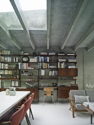 The interior’s white resin floors and concrete walls and ceiling are softened in the dining area by the inclusion of Kai Kristiansen’s rosewood shelving system.